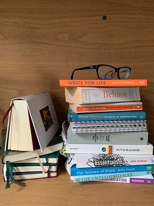 A stack of books with reading glasses on top