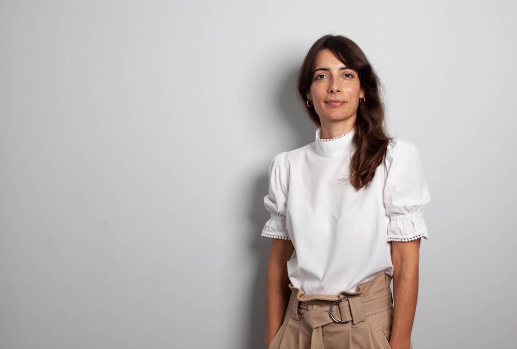 Daphne Maierna standing against a white wall
